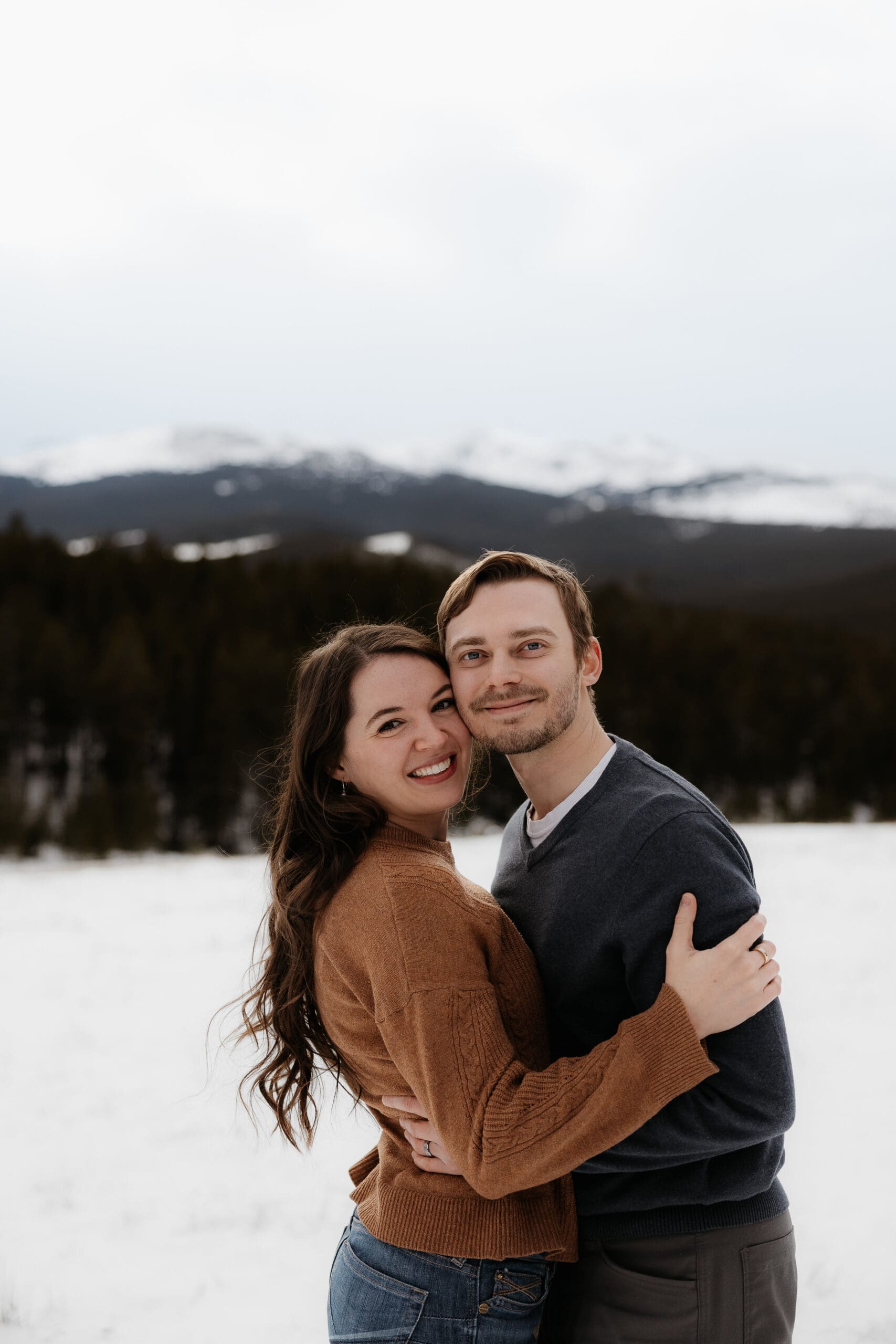 Photograph of man and woman embracing each other and looking at the camera with the Big Horn Mountains in the background.