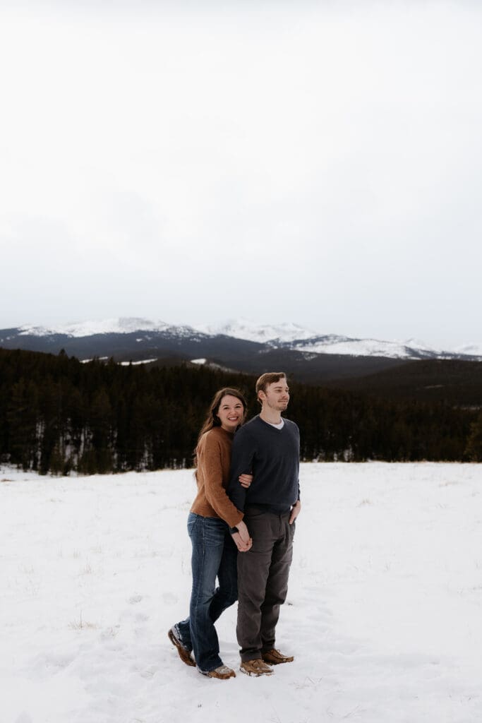 Photograph of engagement session in the Big Horn Mountains where the couple are standing by each other, with the woman smiling at the camera.