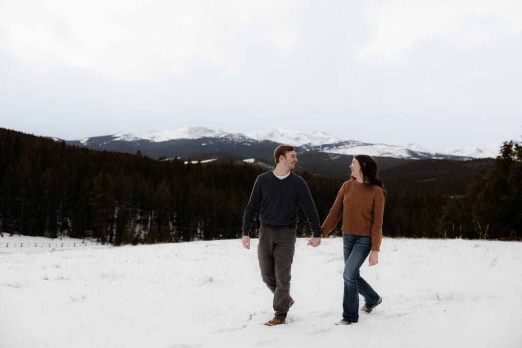 Photograph of engagement session in the Big Horn Mountains where the couple are walking on the snow.