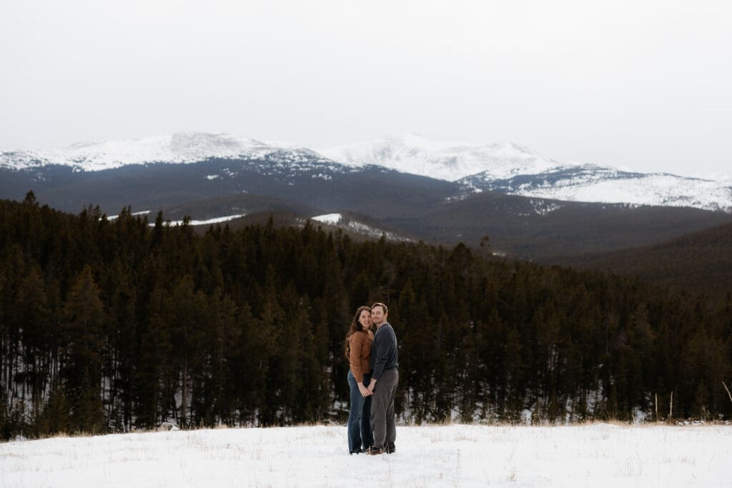 Photograph of engagement session in the Big Horn Mountains where the couple are standing, holding hands, and smiling at the camera.