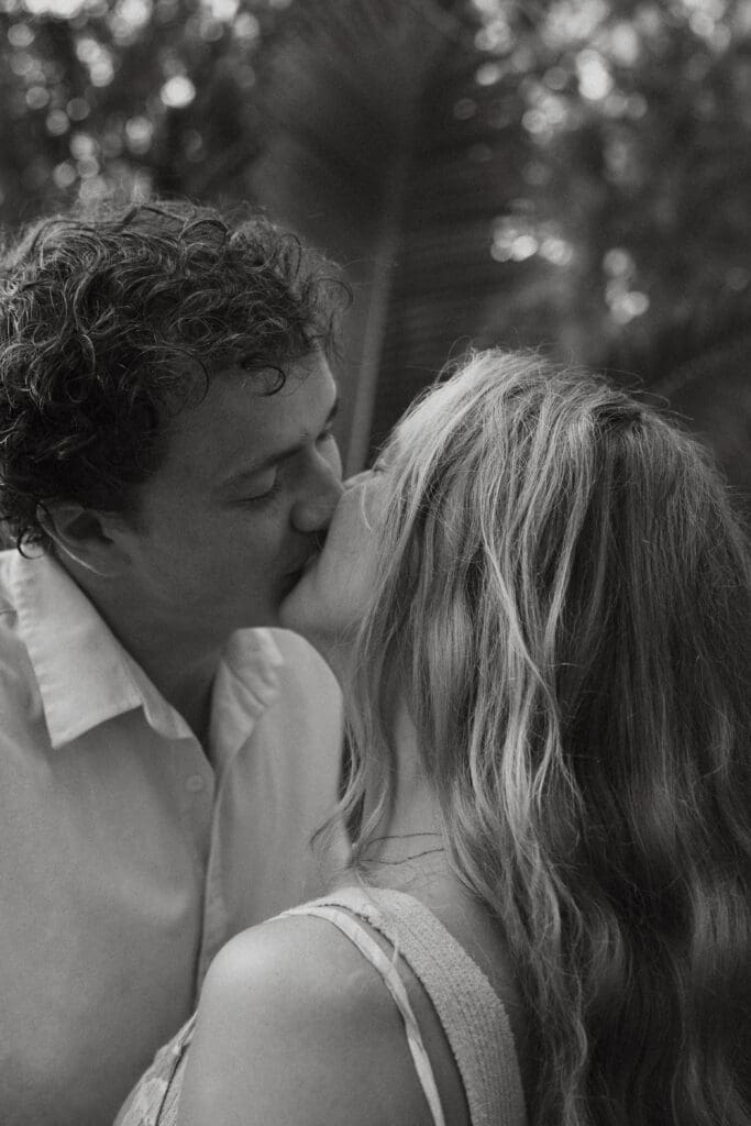 Black and white engagement photo that is close up of the man and woman kissing.