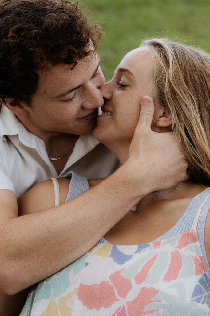 Engagement photo of man holding the woman's face and they are close enough to kiss, but not touching lips.