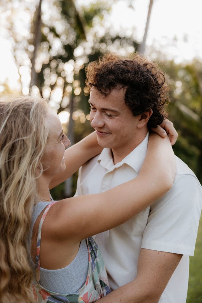 Engagement photo of man gazing at his fiance as he holds her and she wraps her arms around his neck.