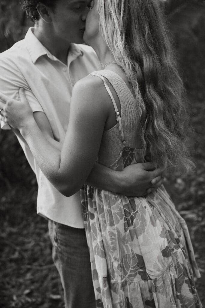 Black and white engagement photo close up photo of man and woman embracing each other and kissing.