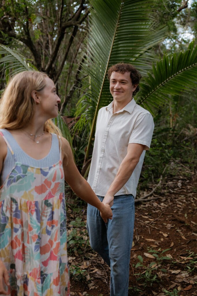 Engagement photo of woman leading the man while the man looks at her and smiles.