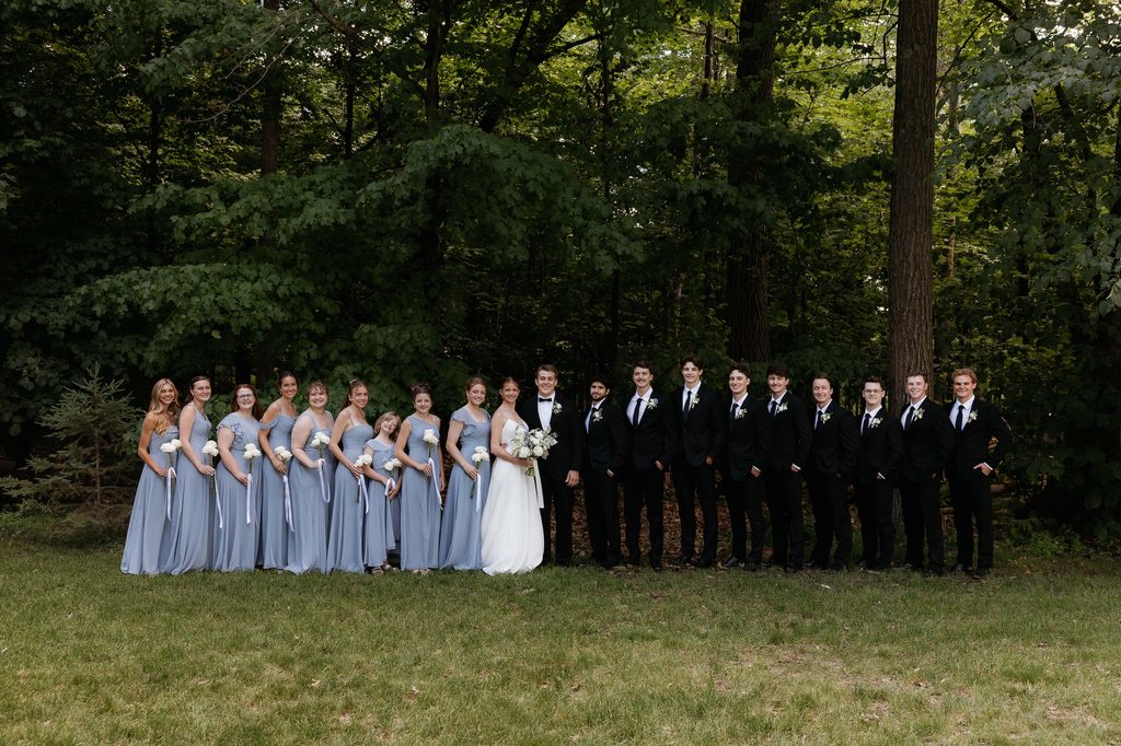 Wedding party standing in a line and smiling at the camera.