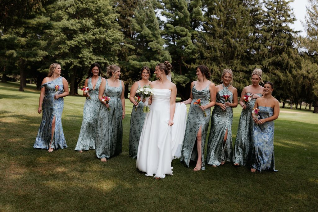 Bridal party walking alongside the bride and laughing.