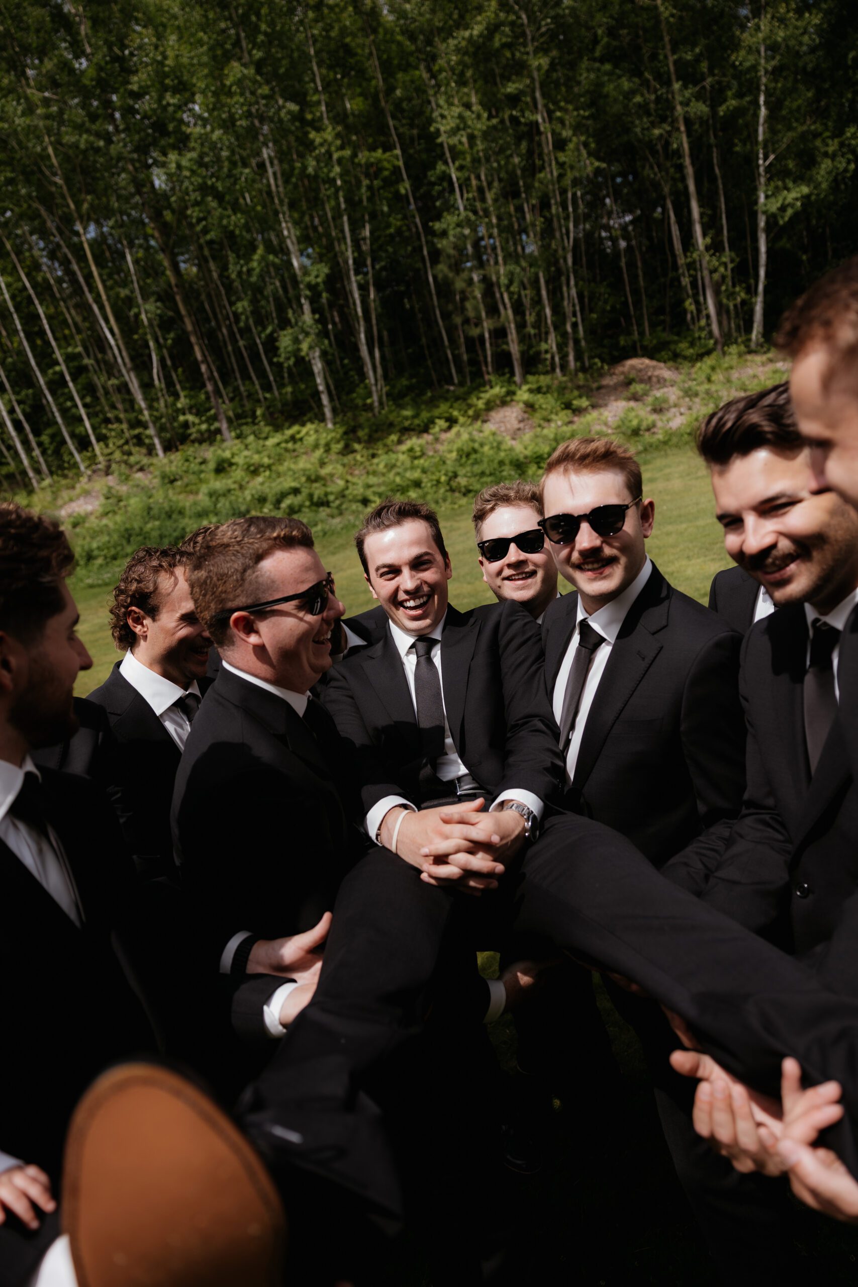 Groomsmen holding groom with everyone smiling.