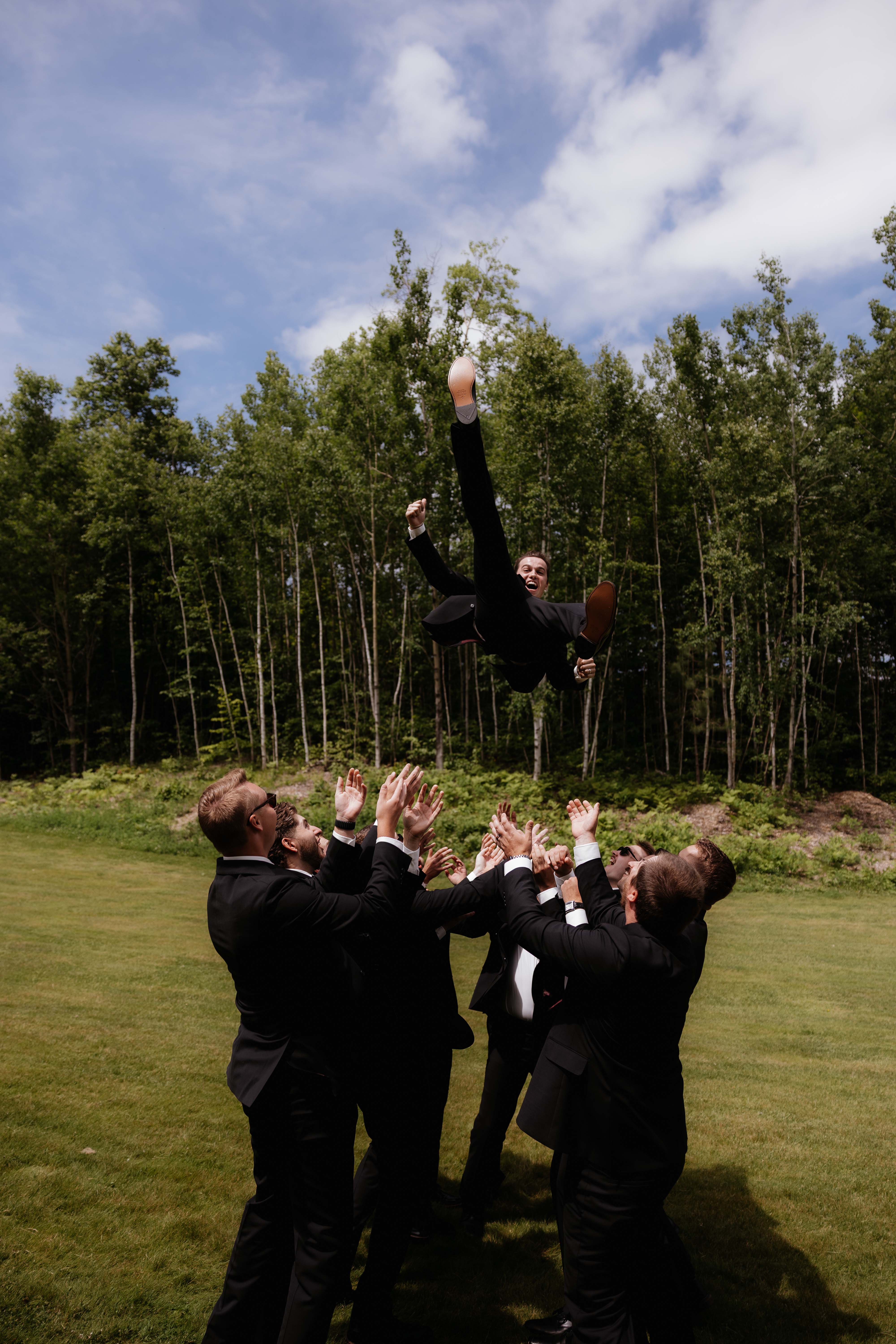 Groomsmen throwing the groom in the air.