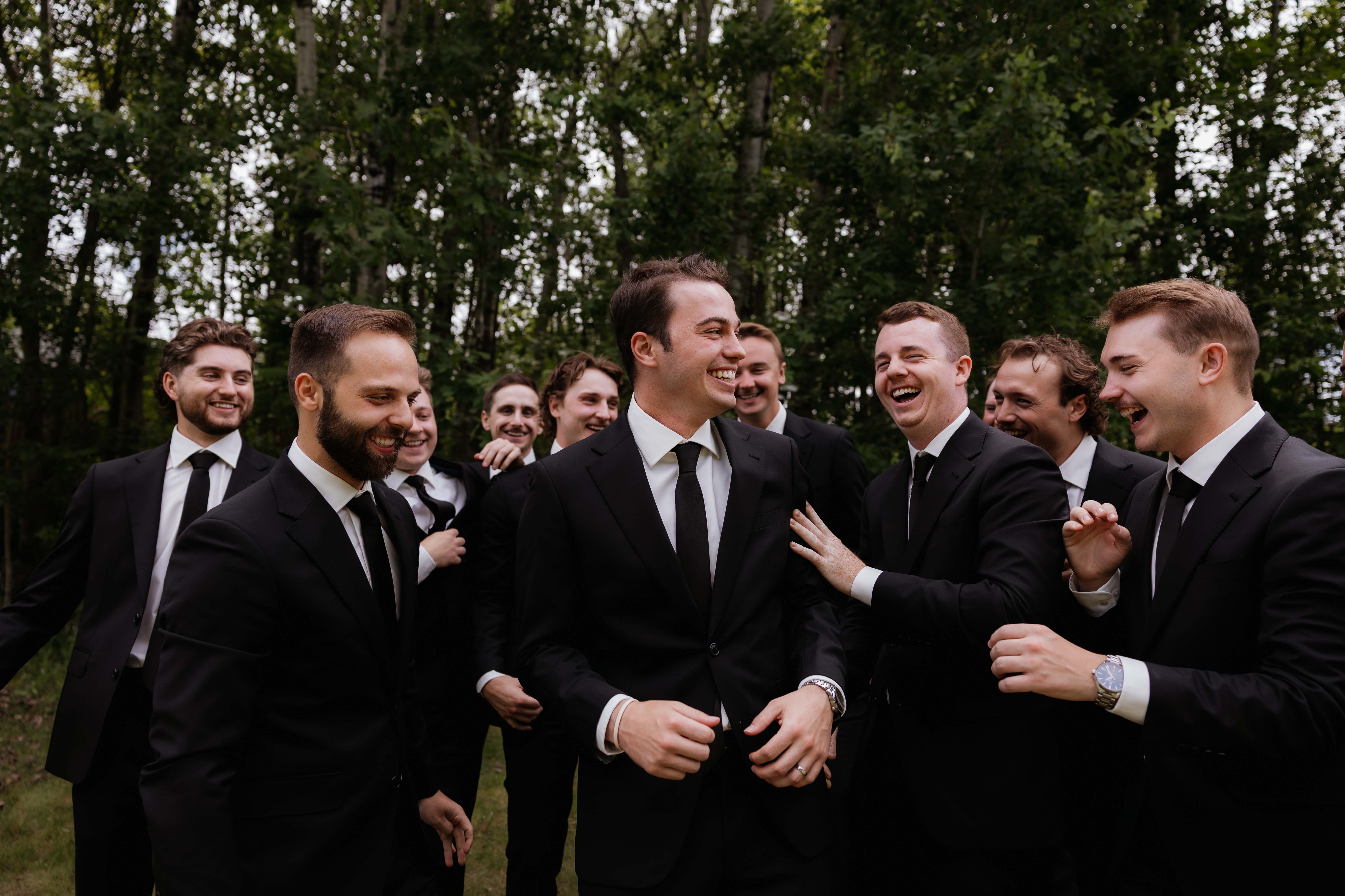 Groomsmen hyping up the groom while laughing together.